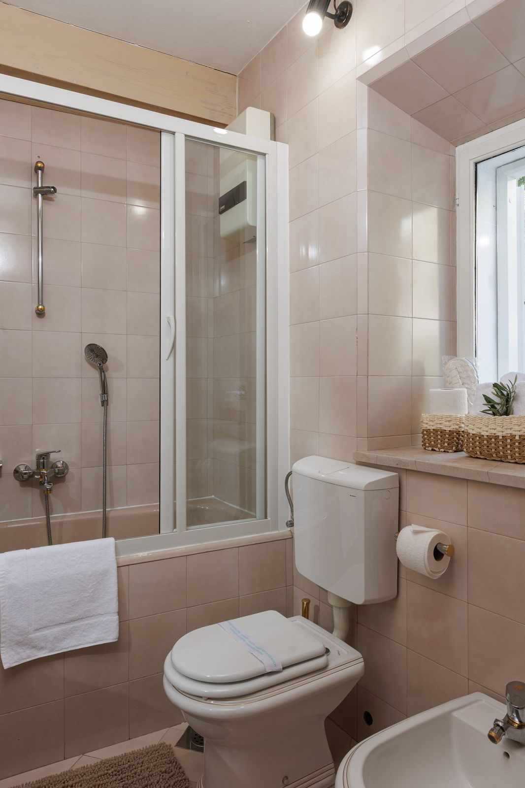 Bathroom with bathtub, sliding shower screen and a window onto the garden