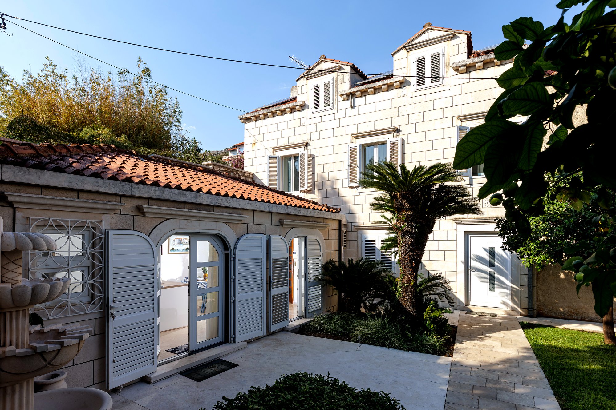 La facciata di Villa LadyM, dimora in pietra dalmata con portico d'ingresso