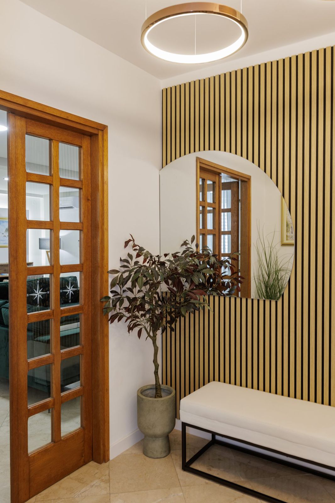 The entrance hall with mirror, wood-slat wall and access to the living room
